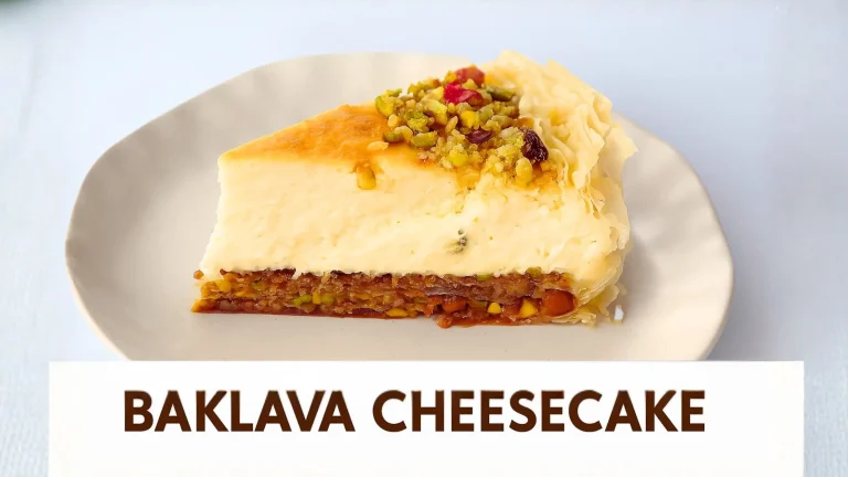 A slice of baklava cheesecake is presented on a white oval plate. The cheesecake has a creamy white top layer, a golden-brown filling, and a flaky pastry crust. It's garnished with chopped pistachios and what appear to be dried cranberries or other small red fruit pieces. Below the plate, a white rectangular banner with a brown border displays the text "BAKLAVA CHEESECAKE" in bold brown letters.