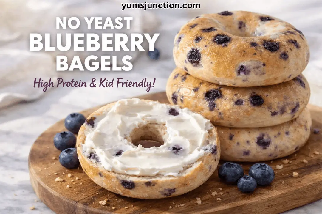 A vertical food graphic titled "NO YEAST BLUEBERRY BAGELS" with the subtitle "High Protein & Kid Friendly!" In the image, a stack of three golden-brown blueberry bagels sits on a wooden board next to a toasted bagel half spread with a thick layer of cream cheese. Fresh blueberries are scattered around the bagels on a marble surface. The website "yumsjunction.com" is at the top.