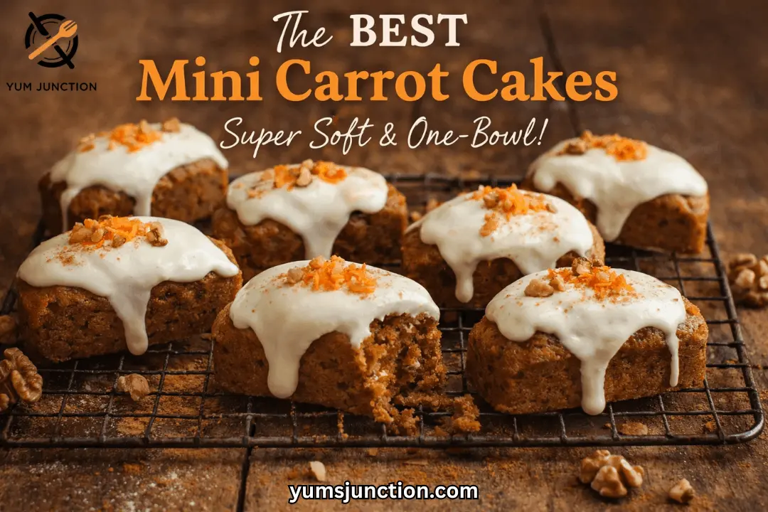 A horizontal food graphic titled "The BEST Mini Carrot Cakes" in bold orange text. Below the title, white script reads "Super Soft & One-Bowl!" The central image shows six mini carrot cakes on a black wire cooling rack over a dark wooden surface. The cakes feature thick white frosting dripping down the sides and are topped with walnuts and shredded carrots. One cake in the foreground has a bite taken out of it. The Yum Junction logo and website address are visible at the top left and bottom center.
