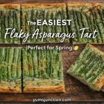 A horizontal promotional graphic titled "The EASIEST Flaky Asparagus Tart (Perfect for Spring)." The image shows slices of the golden, crispy tart on a dark wooden cutting board scattered with lemon zest. A vintage silver server is lifting one slice. Includes the Yum Junction logo and website URL.
