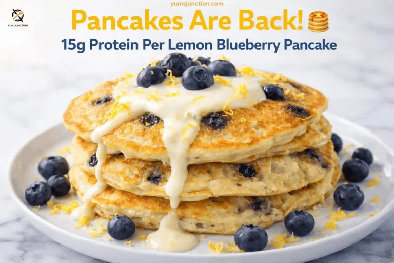 A professional food graphic for Yum Junction featuring a stack of three thick, golden-brown pancakes filled with blueberries. The pancakes are topped with a thick, creamy white glaze that drips down the sides, along with fresh blueberries and yellow lemon zest. The scene is set on a white marble surface with scattered blueberries. Text at the top reads "Pancakes Are Back! 15g Protein Per Lemon Blueberry Pancake" with the website yumsjunction.com included.
