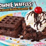 Fun birthday brownie waffles served on a colorful confetti plate, topped with vanilla ice cream, chocolate sauce, and a cherry, perfect for a special breakfast